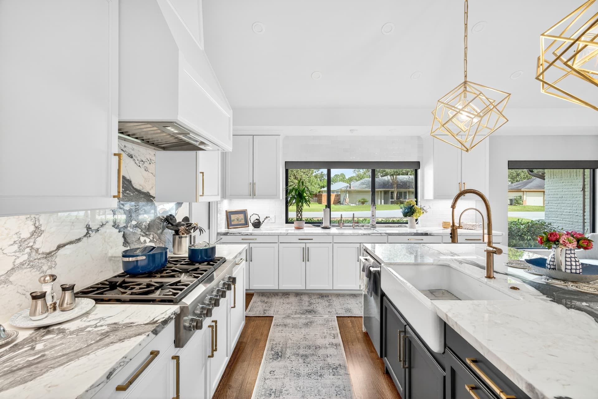 Kitchen view with marble slab backsplash, white cabinetry, farmhouse sink and brass fixtures.